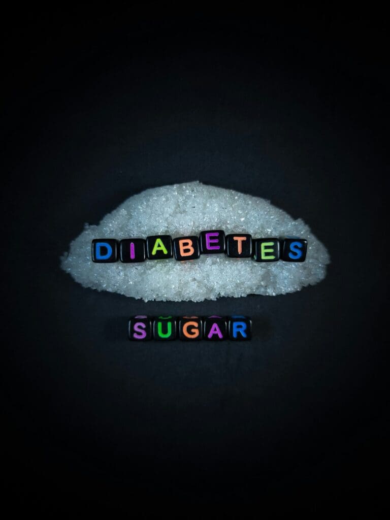 Black bead with color letter in word DIABETES LESS SUGAR with sugar and black background.Top view.