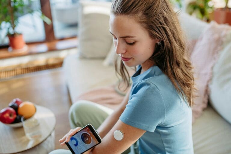 Woman with diabetes checking blood glucose level at home using continuous glucose monitor.