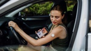 Woman with diabetes checking her blood glucose level before driving car. Diabetic woman connecting