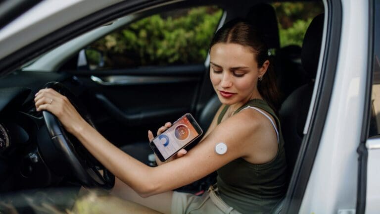 Woman with diabetes checking her blood glucose level before driving car. Diabetic woman connecting