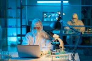 Young modern scientist in protective workwear typing by workplace