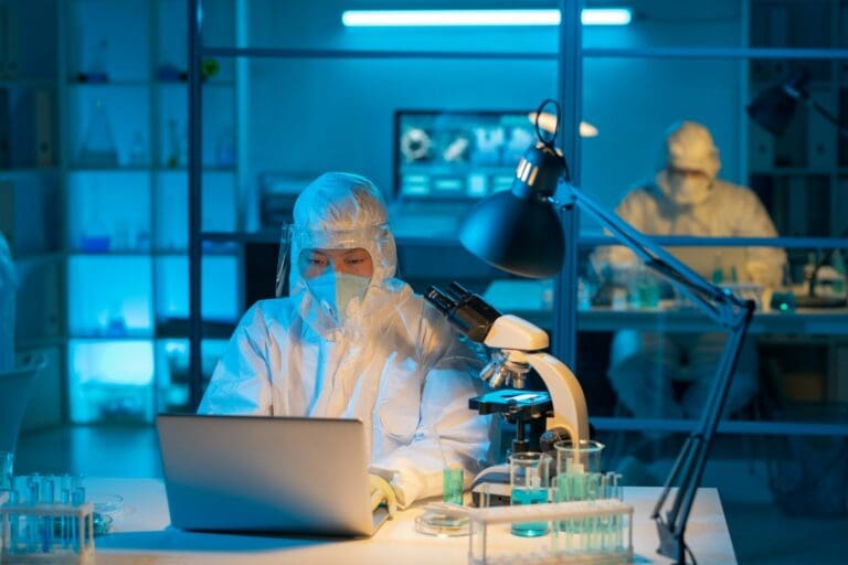 Young modern scientist in protective workwear typing by workplace