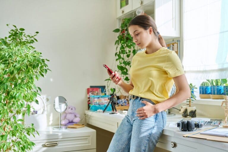 Teenage female using smartphone, resting at home in room, copy space