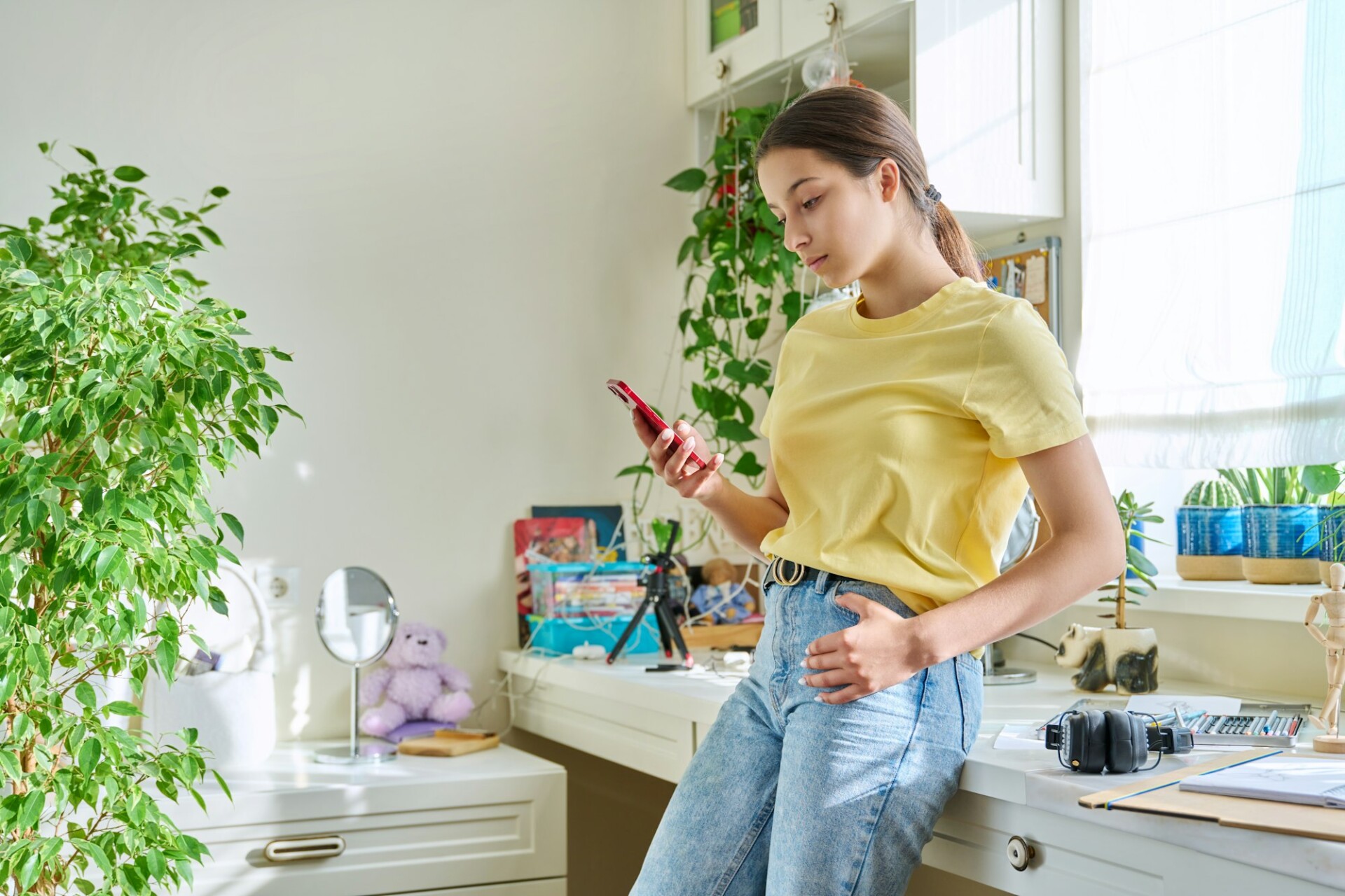 Teenage female using smartphone, resting at home in room, copy space