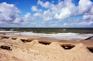 Beach in Ustronie Morskie resort in Poland, a big rusty pipe on the sandy beach in the foreground