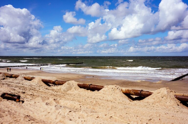 Beach in Ustronie Morskie resort in Poland, a big rusty pipe on the sandy beach in the foreground