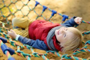 Cute little blond caucasian boy having fun on outdoor playground.